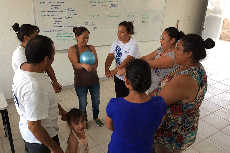 Grupo de padres de familia en salón de clases realizando una dinámica