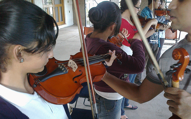 Instructor de Violín corrigiendo postura de alumno